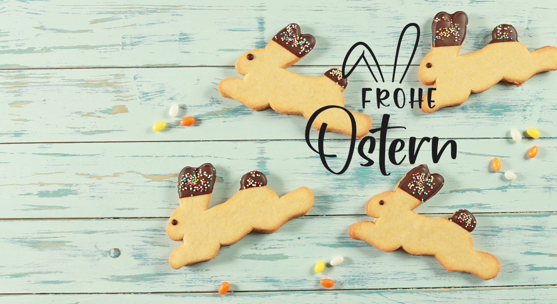 Vier Hasikekse liegen zwischen kleinen bunten Ostereiern auf einem türkischen Holzuntergrund