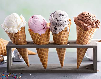 Vier Eiswaffeln mit je einer Kugel Vanille-, Erdbeer, Stracciatella- und Schokoladeneis stehen in einem Metallständer