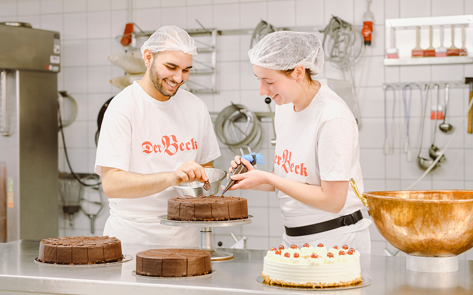 Zwei Konditoren verzieren eine Torte