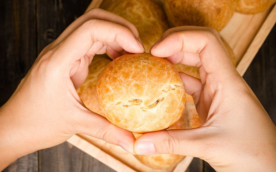 Hände in Herzform halten ein Brötchen 