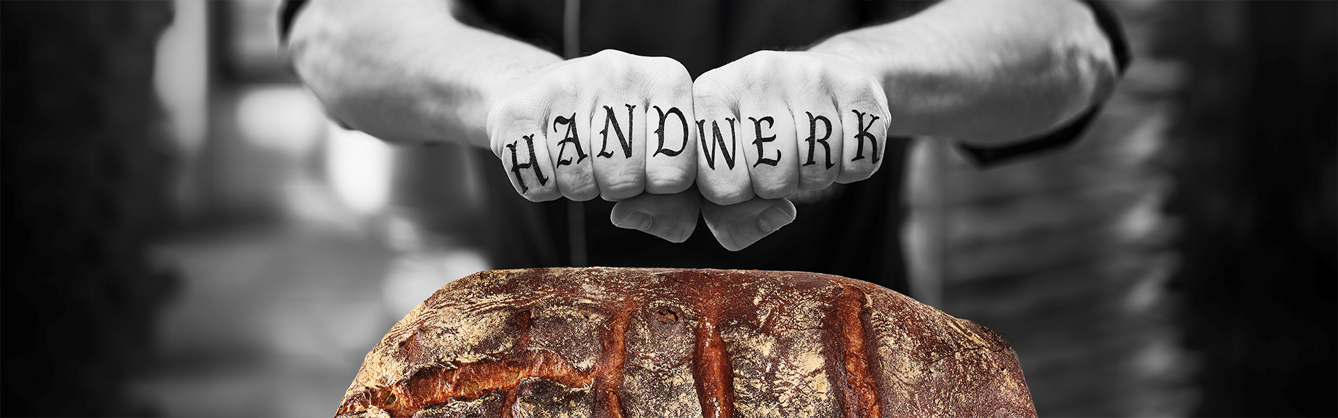Bäckerhände mit tätowiertem Wort "Handwerk" über einem Brot